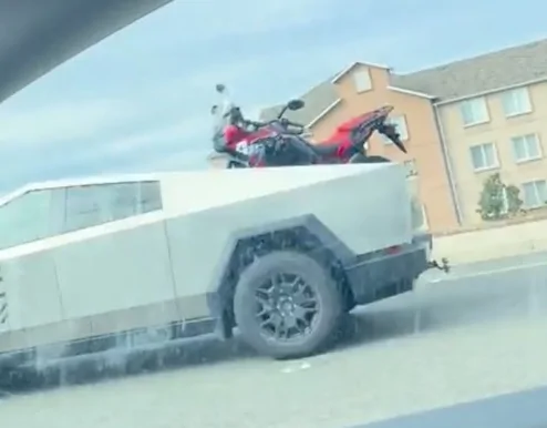 Tesla Cybertruck Cybertruck hauling big motorcycle (Honda Adventure) in its bed F9Vanzaa4AA7l_G