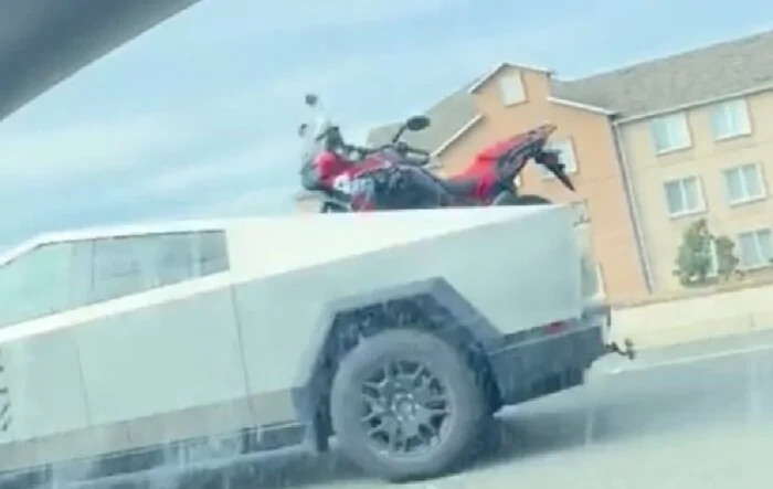 Cybertruck hauling big motorcycle (Honda Adventure) in its bed